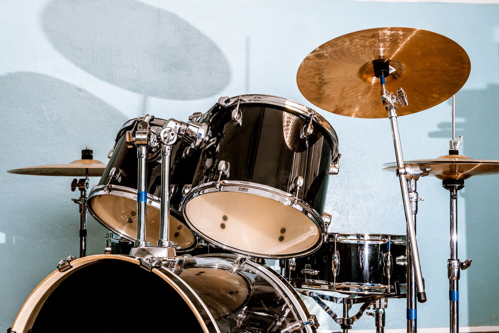 black drums blue wall black acoustic drum kit in front of a blue wall